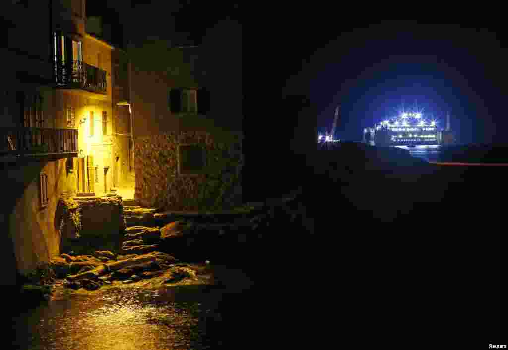 The Costa Concordia (R) cruise liner is seen at Giglio harbor at Giglio Island, Italy, early Friday.&nbsp; Preparations to tow away the ship continued on Thursday, with engineers connecting the last chains and cables to the sponsons, the large metal boxes attached to the wreck.