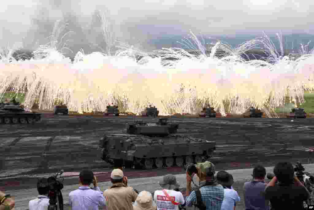 A line of tanks from the Japan Ground Self-Defense Force flare up a smokescreen during an annual live- firing exercise at Higashi Fuji training range in Gotemba, southwest of Tokyo.