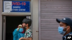 11일 인도 스리나가르에서 신종 코로나바이러스 검사 요원이 주민의 코에서 검체를 채취하고 있다.