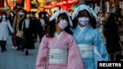 Visitors wearing protective face masks walk under decorations for the New Year at Nakamise street leading to Senso-ji temple at Asakusa district, a popular sightseeing spot, amid the coronavirus disease (COVID-19) pandemic, in Tokyo, Dec. 24, 2021. 