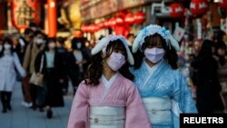 Visitors wearing protective face masks walk under decorations for the New Year at Nakamise street leading to Senso-ji temple at Asakusa district, a popular sightseeing spot, amid the coronavirus disease (COVID-19) pandemic, in Tokyo, Dec. 24, 2021. 