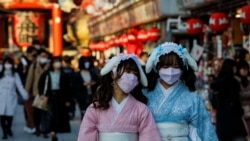 Visitors wearing protective face masks walk under decorations for the New Year at Nakamise street leading to Senso-ji temple at Asakusa district, a popular sightseeing spot, amid the coronavirus disease pandemic, in Tokyo, Dec. 24, 2021.