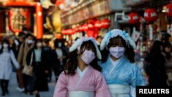 Visitors wearing protective face masks walk under decorations for the New Year at Nakamise street leading to Senso-ji temple at Asakusa district, a popular sightseeing spot, amid the coronavirus disease pandemic, in Tokyo, Dec. 24, 2021.