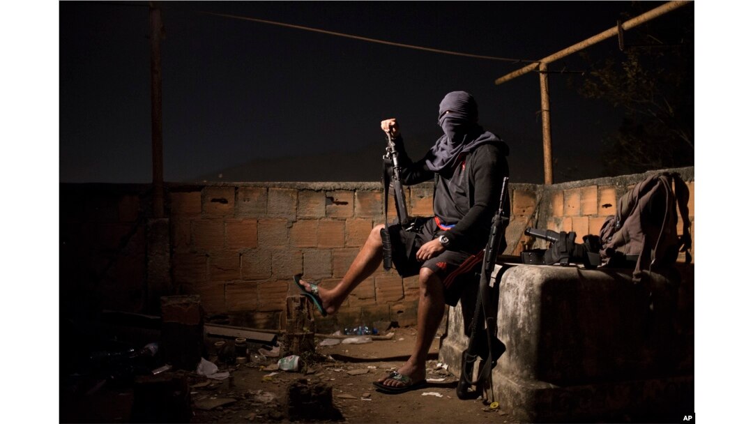 A drug gang leader poses for a photo, July 6, 2016, in a slum in Rio de Janeiro, Brazil. He told the Associated Press that drug dealers win the hearts and minds of locals by paying for food and medicine.