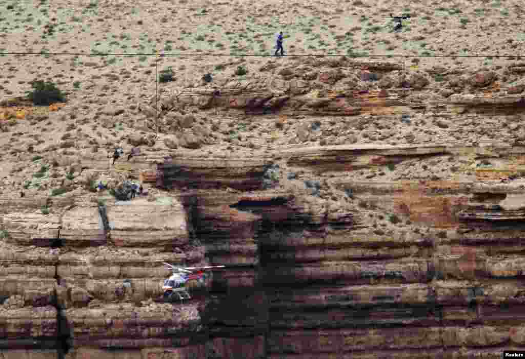 Daredevil Nik Wallenda walks on a two-inch (5-cm) diameter steel cable rigged 1,400 feet (426.7 meters) across more than a quarter-mile deep remote section of the Grand Canyon near Little Colorado River, Arizona, June 23, 2013. 