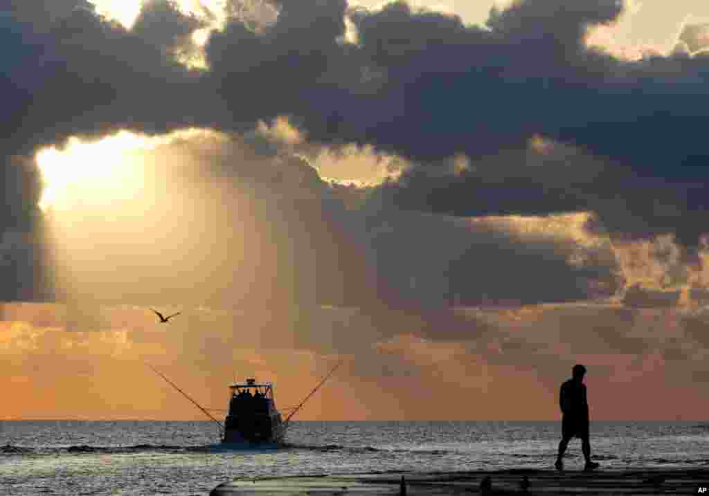 A fishing boat heads out to sea as the sun rises in Bal Harbour, Florida, USA.