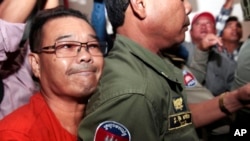 Hong Sok Hour, left, a senator from the opposition Cambodia National Rescue Party, is escorted by riot police officers, center, at Phnom Penh Municipal Court in Phnom Penh, Cambodia, Oct. 2, 2015.