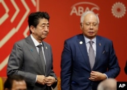 Japan's Prime Minister Shinzo Abe (left) and Malaysia's Prime Minister Najib Razak leave after a meeting between leaders of the Asia Pacific Economic Cooperation, APEC, and regional business leaders, in Lima, Peru, Nov. 19, 2016.