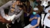 Kapolsek Galih Apria memberikan hadiah ayam kepada Jeje Jaenudin, warga Desa Sindanglaya, menerima suntikan dosis pertama vaksin COVID-19, saat program vaksinasi jemput bola di Kabupated Cianjur, Jawa Barat, Selasa, 15 Juni 2021. (Foto: Willy Kurniawan/Re