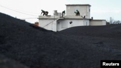 Spanish military clean ash from the Cumbre Vieja volcano as they stand on the roof of a house in a neighborhood of Las Manchas, on the Canary Island of La Palma, Spain, Dec. 16, 2021.