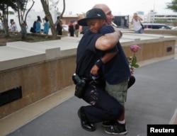 FILE - A Dallas Police officer hugs a child who came to pay respects at a makeshift memorial at Dallas Police Headquarters following the multiple police shootings in Dallas, Texas, July 9, 2016.