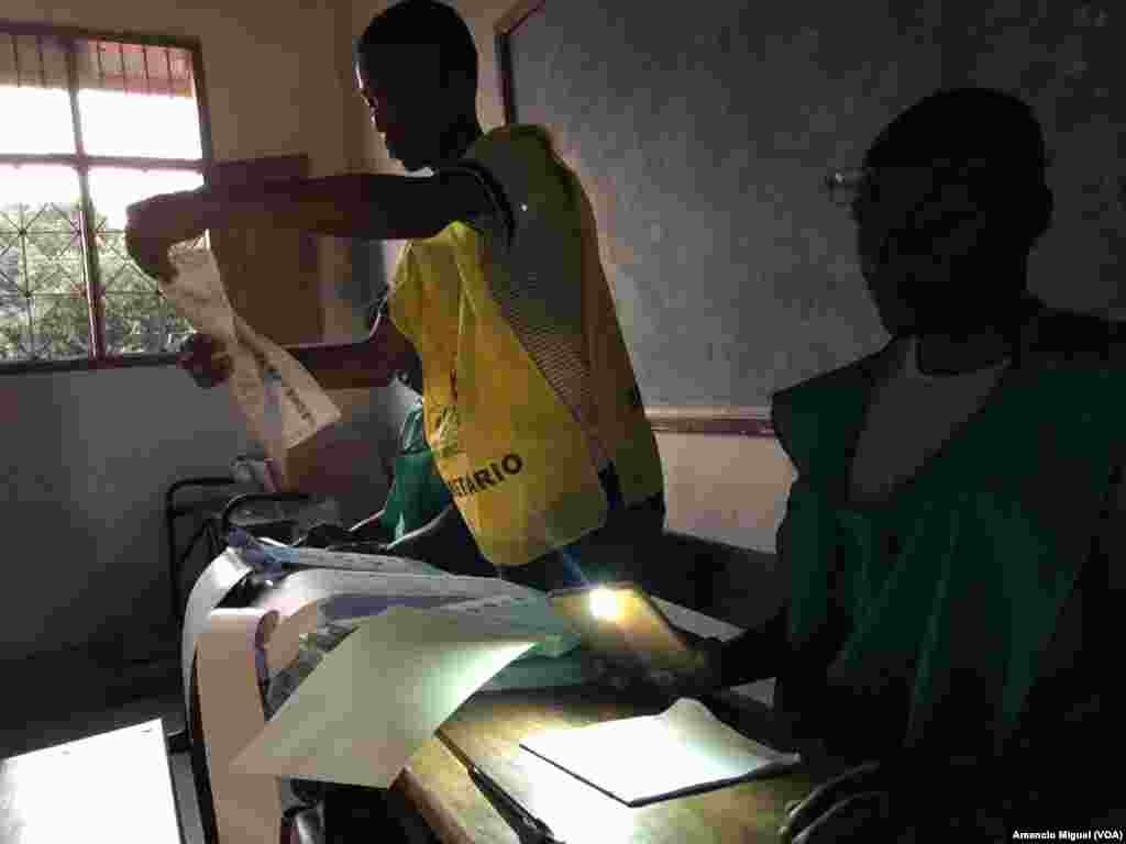 Funcionários de assembleia de voto usam lanterna de telefone para confirmar dados em boletim de voto. Wimby, Cabo Delgado, Moçambique. 15 Outubro 2019