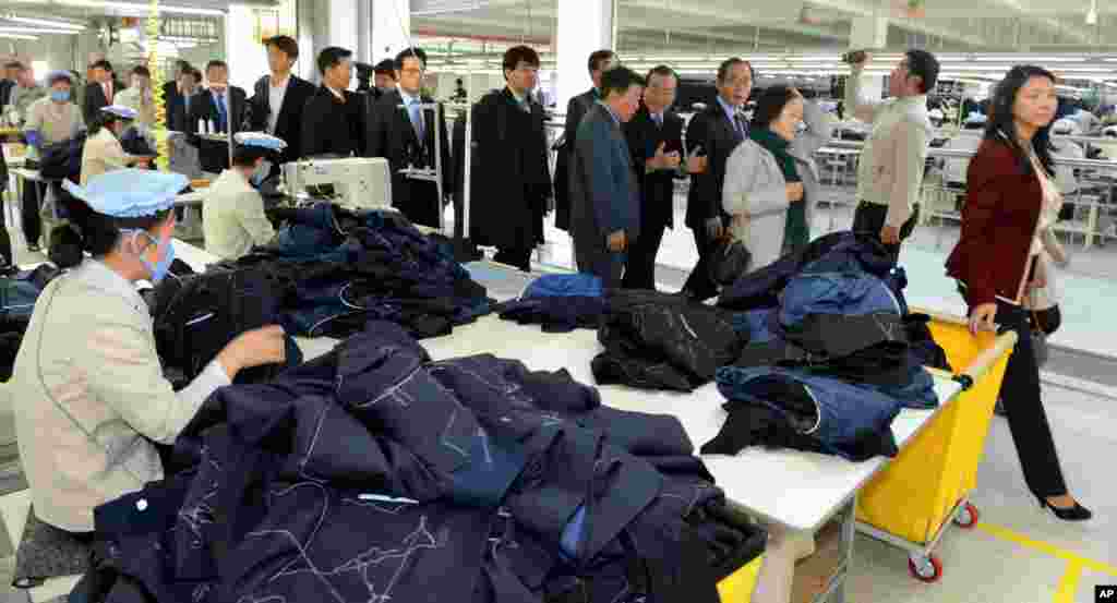 South Korean lawmakers walk past North Korean workers at a factory in the inter-Korean industrial park in Kaesong, North Korea, Oct. 30, 2013.