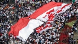 Warga Indonesia mengibarkan bendera nasional merah putih besar dan yang lebih kecil saat unjuk rasa di Jakarta, Indonesia, Minggu, 4 Desember 2016. (Foto: AP)