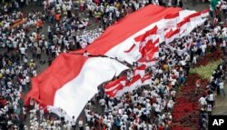 Para peserta pawai menggelar bendera merah-putih raksasa dalam pawai mendukung persatuan Indonesia, di Jakarta, 4 Desember 2016.