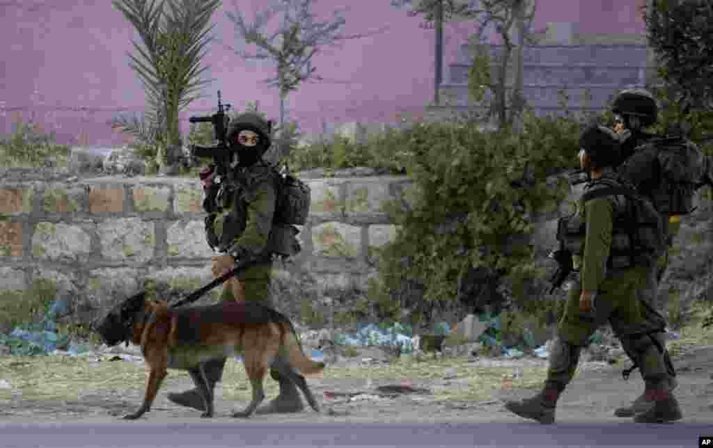 Israeli soldiers walk during an operation in the Balata refugee camp in the West Bank city of Nablus, June 17, 2014.