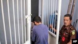 A security official from the prosecutor's office escorts two men accused of having gay sex into a holding cell to wait for the start of their trial at Sharia court in Banda Aceh, Indonesia, May 10, 2017.