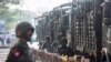 FILE - Soldiers stand next to military vehicles as people gather to protest against the military coup, in Yangon, Myanmar, Feb. 15, 2021.