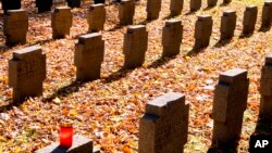 A candle rests on a tombstone in a field of graves belonging to WWI soldiers in the main cemetery in Frankfurt, Germany, Nov. 3, 2018. German Chancellor Angela Merkel will mark the 100th anniversary of the end of World War I on French soil, and President Frank-Walter Steinmeier will be in London’s Westminster Abbey. But in Germany, there are no national commemorations planned because the armistice did not bring peace to Germany.