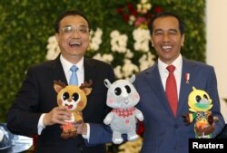 中国总理李克强和印度尼西亚总统佐科·维多多在印尼总统府分享轻松时刻，手持2018年亚运会的吉祥物。（2018年5月7日）