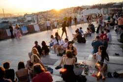 People watch the sun set from a viewpoint overlooking the Tagus river in Lisbon, Oct. 8, 2021. Portugal has scrapped many of its remaining COVID-19 restrictions, after becoming the world leader in the vaccination rollout.