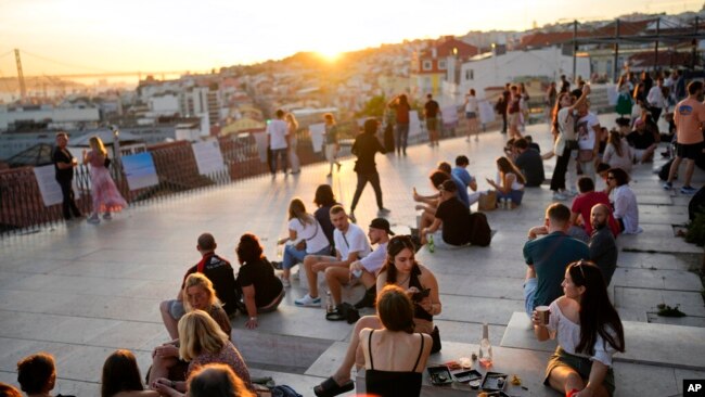 People watch the sun set from a viewpoint overlooking the Tagus river in Lisbon, Oct. 8, 2021. Portugal has scrapped many of its remaining COVID-19 restrictions, after becoming the world leader in the vaccination rollout.