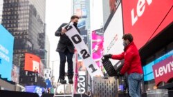 Jonathan Bennett, host of Good Riddance Day, left, and Joe Papa, Director of Events, Times Square Alliance burn a 2021 banner at the official Good Riddance Day celebration in Times Square, Tuesday, Dec. 28, 2021, in New York.