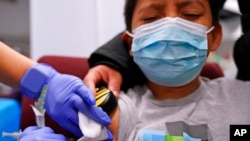 FILE - Julian Salgado, 7, receives his second dose of the Pfizer COVID-19 vaccine from Lurie Children's hospital registered nurse Elvia Cervantes at Northwest Community Church in Chicago, Dec. 11, 2021.