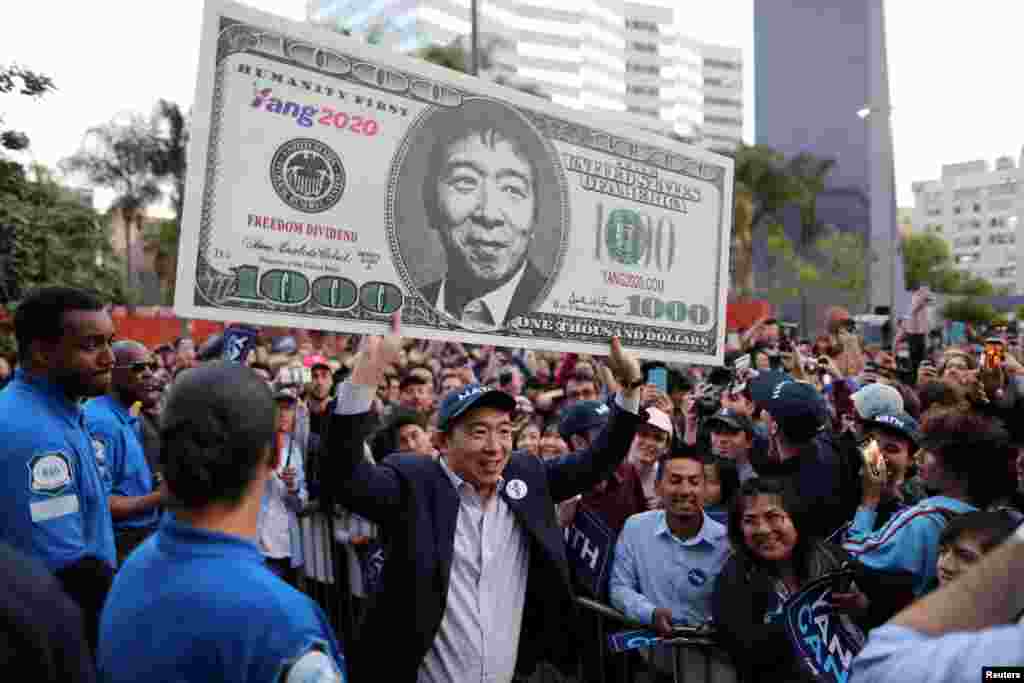 U.S. Democratic presidential candidate Andrew Yang hoists a supporter&#39;s sign after speaking at a rally in downtown Los Angeles, California, April 22, 2019.