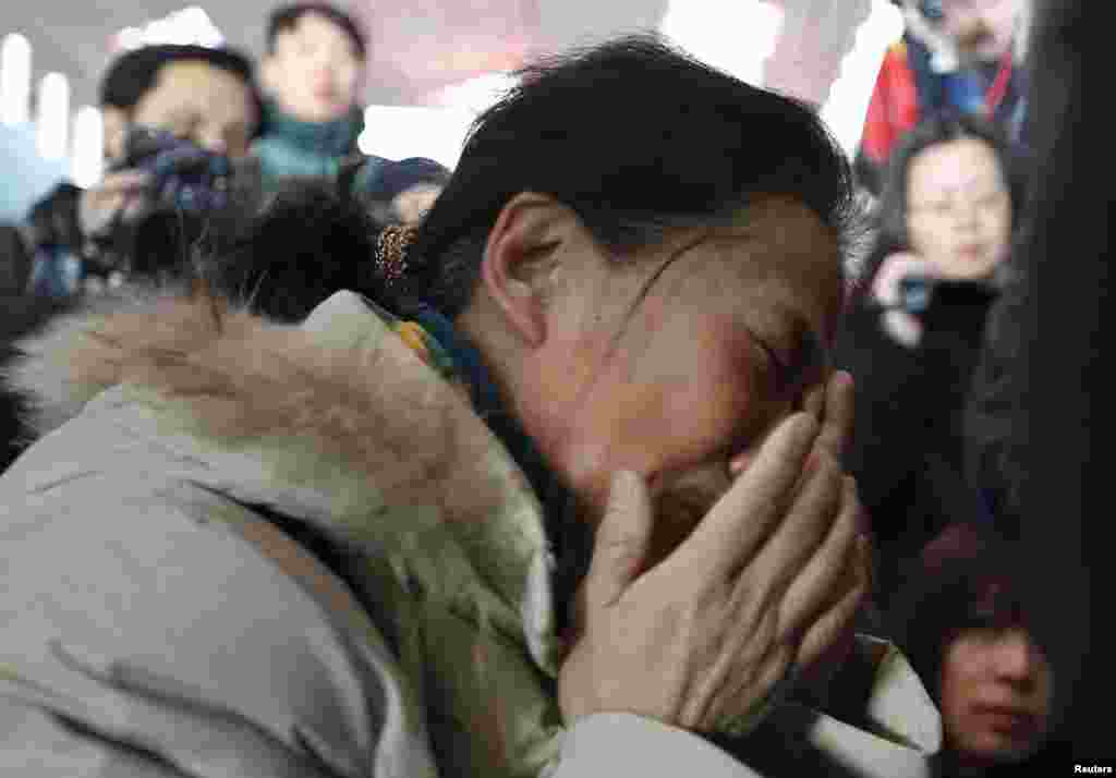 Seorang kerabat penumpang Malaysia Airlines penerbangan MH370 menangis, dikelilingi oleh wartawan di Bandar Udara Internasional Beijing.