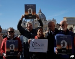 Sex abuse survivors and members of ECA (Ending Clergy Abuse), hold banners in front of St. Peter's Square at the Vatican, Feb. 24, 2019.
