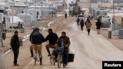 Syrian refugees travel on the main street of Al Zaatari refugee camp in the Jordanian city of Mafraq, near the border with Syria, Jan. 15, 2015.