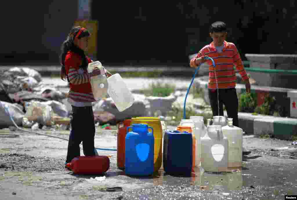 Children fill their containers during a water shortage, in Aleppo, April 6, 2014.&nbsp;