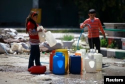 FILE - Children fill containers with water during a water shortage in the old city of Aleppo, Apr. 6, 2014.