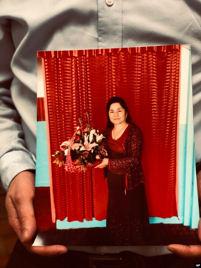 Ferkat Jawdat holds up a photo of his mother during a gathering to raise awareness about loved ones who have disappeared in China's far west, in Washington D.C., Feb. 24, 2019.