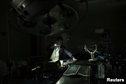 A nurse uses light from a phone while he looks for material in an out-of-use operating room of the Padre Justo hospital, during a blackout in Rubio, Venezuela, March 14, 2018.