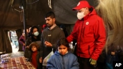 Migrants receive food inside a Red Cross tent near a logistics center at the checkpoint "Kuznitsa" at the Belarus-Poland border near Grodno, Belarus, Nov. 21, 2021.