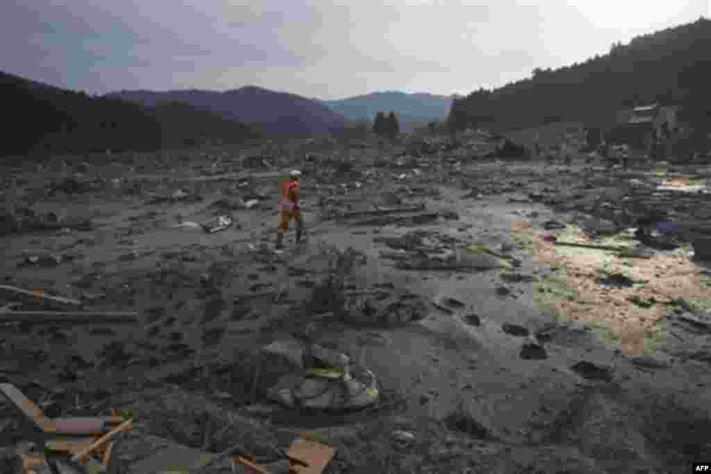 A Japanese rescue team member walks through the completely leveled village of Saito in northeastern Japan Monday, March 14, 2011. Rescue workers used chain saws and hand picks Monday to dig out bodies in Japan's devastated coastal towns, as Asia's richest