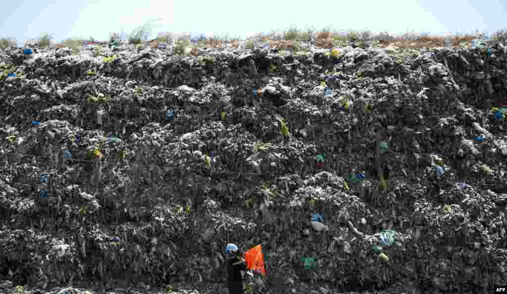 A man carrying his son walks in front of a landfill near Manila Bay, Philippines.