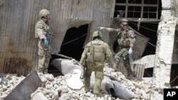 Soldados de la OTAN investigan la escena del ataque talibán de este miércoles, anunciado como respueta a la visita del presidente Barack Obama.