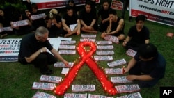 Seorang pendeta menyalakan lilin di sekitar simbol kesadaran atas HIV/AIDS dalam peringatan Hari AIDS Sedunia di Quezon City (1/12). 