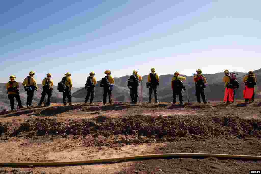 Firefighters from Mexico rest while hiking to their destination to cut a containment line in the Tarzana area during the Palisades Fire in Los Angeles, California, Jan. 13, 2025.