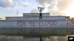 En esta foto de archivo del 1 de junio de 2020, un manifestante enmascarado alza una bandera durante una protesta contra el gobierno del presidente Daniel Ortega en Managua, Nicaragua. 