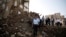Peter Maurer, the president of the International Committee of the Red Cross, center, walks near houses destroyed by a Saudi-led airstrike during his visit to the old city of Sana'a, Yemen, Aug. 9, 2015.