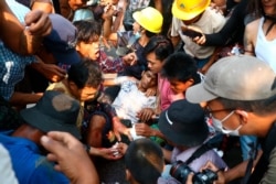 Anti-coup protesters surround an injured man in Hlaing Thar Yar township in Yangon, Myanmar, March 14, 2021.