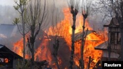 Flames and smoke billow from residential houses after they caught fire during a gunbattle between Indian army soldiers and suspected militants at Kachdoora village in south Kashmir's Shopian district, Apr. 1, 2018.