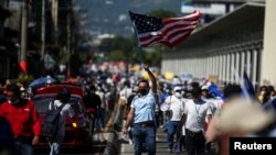 Un hombre ondea una bandera estadounidense durante una protesta contra acciones del gobierno del presidente de El Salvador, Nayib Bukele, como el uso de bitcoin y reformas legales para extender su mandato, en San Salvador, El Salvador, el 12 de diciembre de 2021.