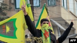 FILE - Syrian Kurds flash the V for victory sign as they celebrate the fall of capital Damascus to rebel fighters, in the city of Qamishli on Dec. 8, 2024.