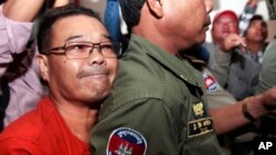 Hong Sok Hour (l) a senator from the opposition Cambodia National Rescue Party, is escorted by riot police officers, center, at Phnom Penh Municipal Court in Phnom Penh, Cambodia, Oct. 2, 2015. 