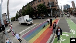 FILE - Pedestrians cross a street on a rainbow crosswalk in Seattle's Capitol Hill neighborhood, June 5, 2018. A New Jersey town has followed suit.